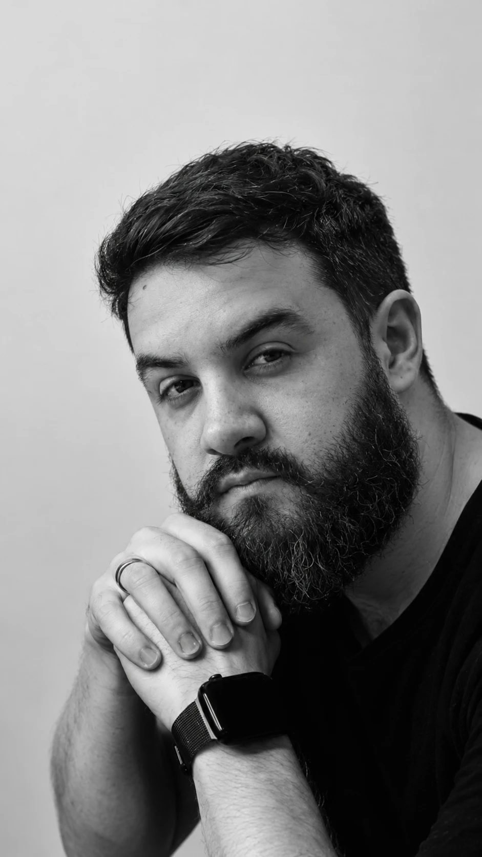 Lucas Pacheco, fundador da Revind, de barba e camiseta preta, com as mãos apoiadas no queixo.